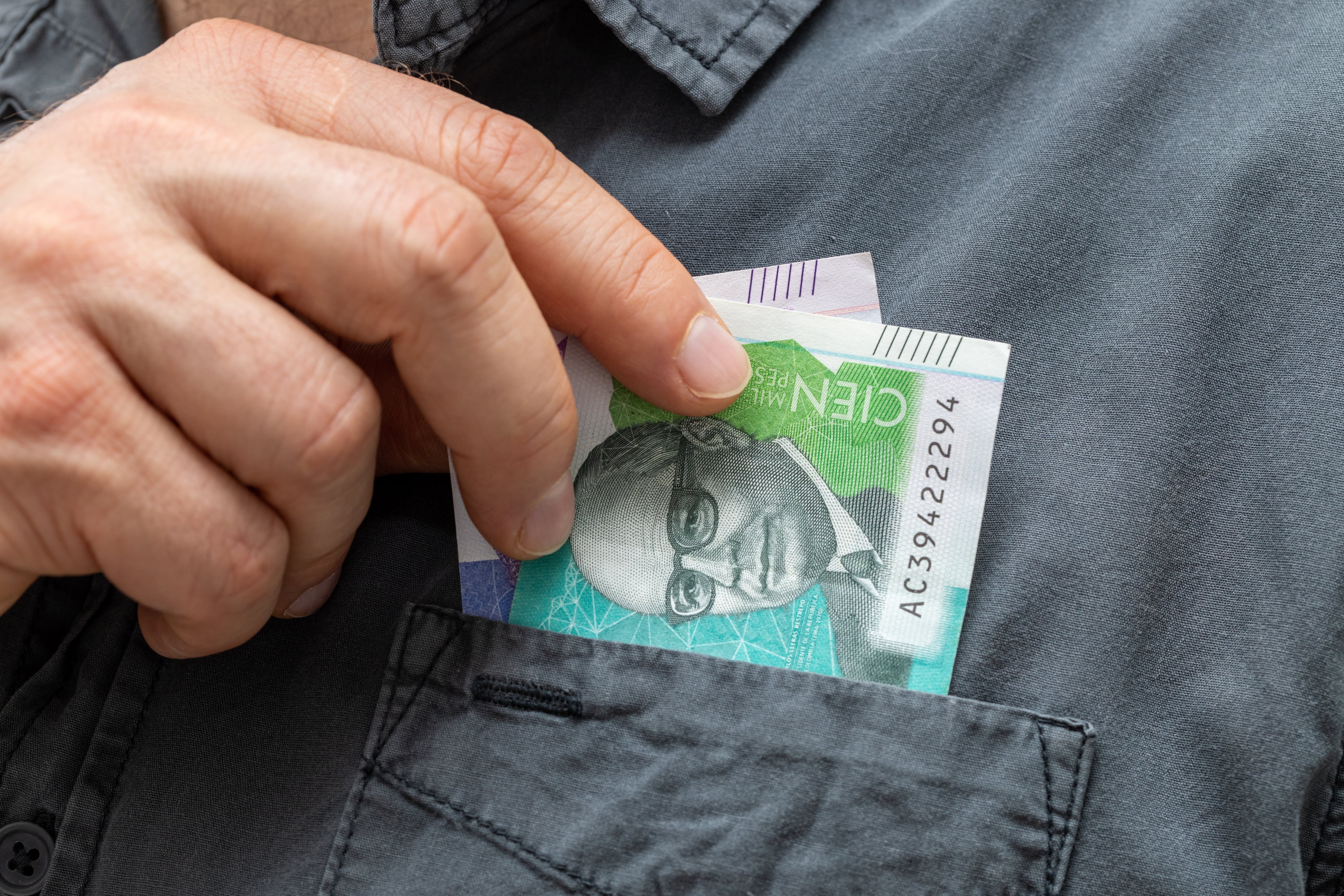 Colombia money, Man takes banknotes from his shirt pocket, 50 and 100 Colombian pesos, Close up, Business and financial concept