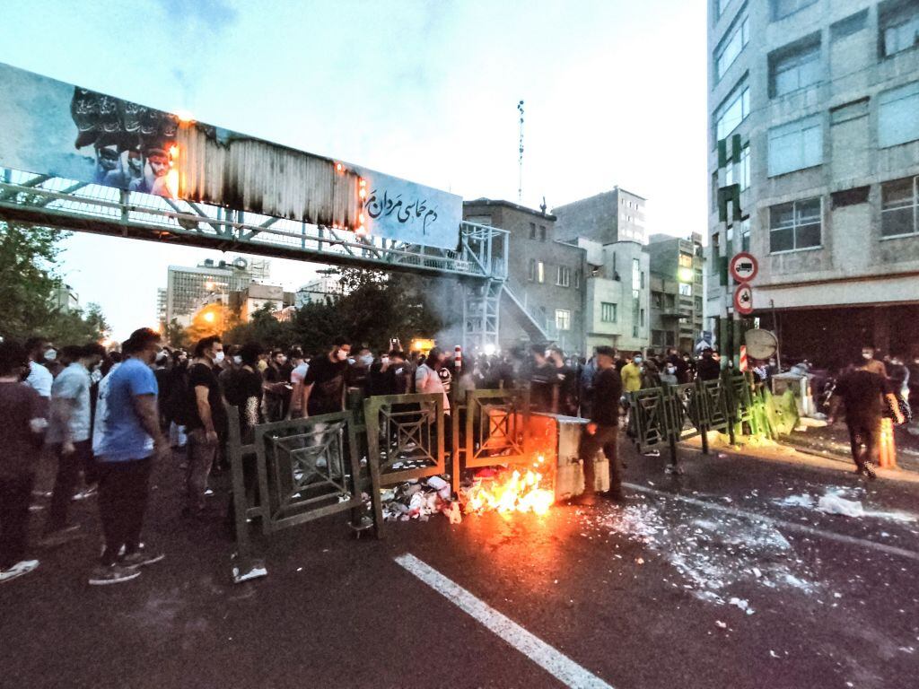 A picture obtained by AFP outside Iran on September 21, 2022, shows Iranian demonstrators burning a rubbish bin in the capital Tehran during a protest for Mahsa Amini, days after she died in police custody. - Protests spread to 15 cities across Iran overnight over the death of the young woman Mahsa Amini after her arrest by the country's morality police, state media reported today.In the fifth night of street rallies, police used tear gas and made arrests to disperse crowds of up to 1,000 people, the official IRNA news agency said. (Photo by AFP) (Photo by -/AFP via Getty Images)