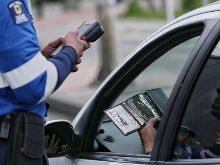 Agente Civil de Tránsito revisando que la documentación vehicular esté vigente (Foto vía Colprensa)
