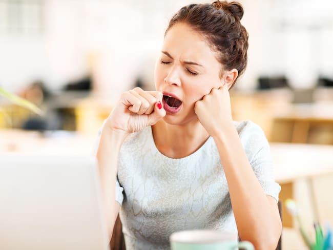 Mujer bostezando en el trabajo, después de comer (Getty Images)