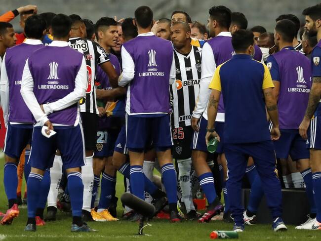 Los jugadores de Boca Juniors y los de Atlético Mineiro se enfrentan mientras el árbitro revisa el VAR.
