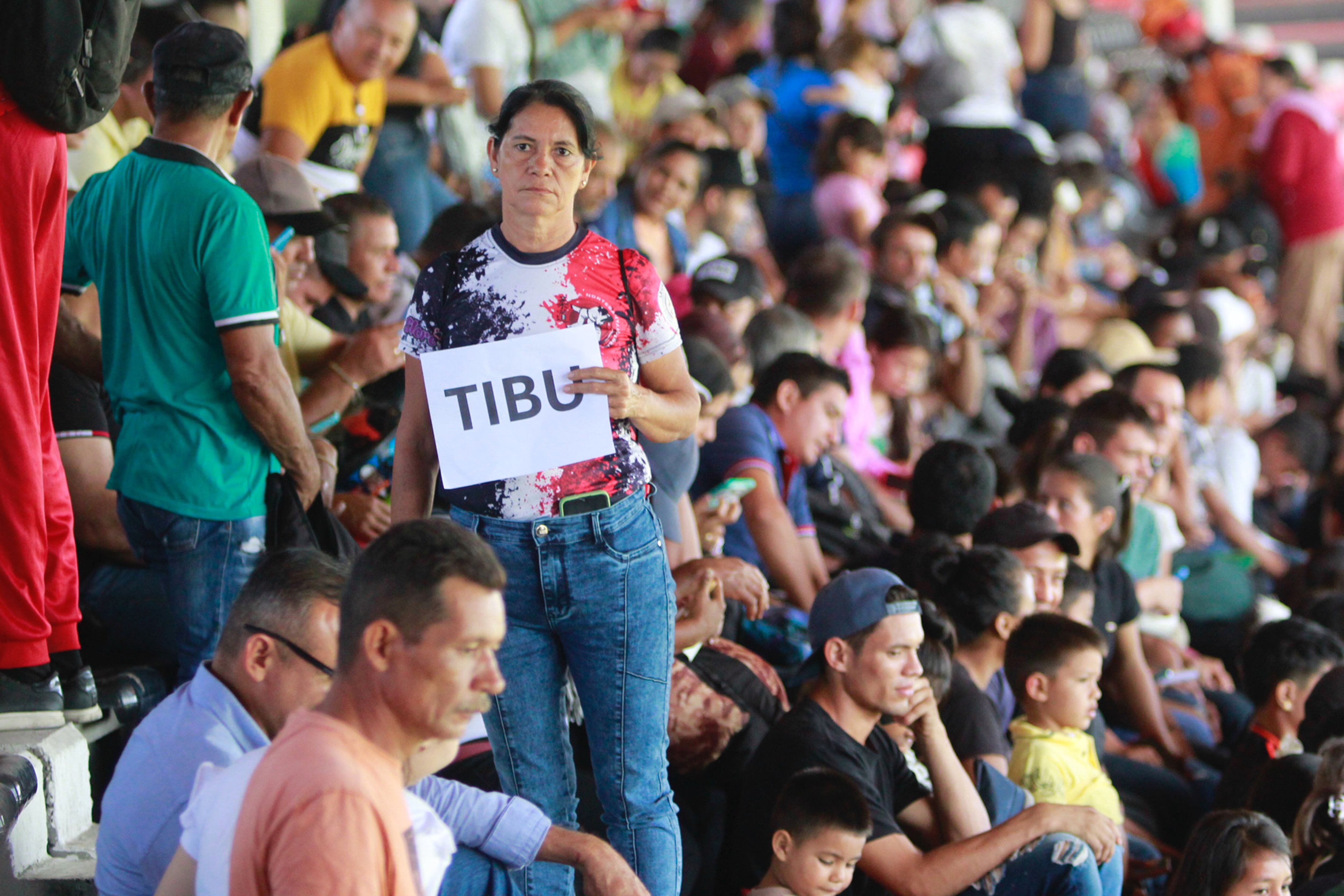 -FOTODELDÍA- AME2505. CÚCUTA (COLOMBIA), 19/01/2025.- Una mujer desplazada por la violencia sostiene un cartel en el estadio General Santander este domingo, en Cúcuta (Colombia). La ciudad de Cúcuta, limítrofe con Venezuela, se ha convertido en un símbolo del sufrimiento humano causado por el conflicto armado en la región del Catatumbo y es el lugar donde en los últimos días han llegado centenares de personas huyendo de la violencia desatada entre la guerrilla del Ejército de Liberación Nacional (ELN) y una disidencia de las FARC. EFE/ Mario Caicedo