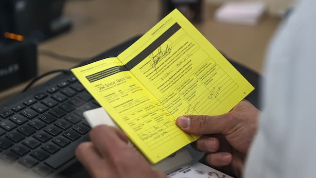 QUI01. QUITO (ECUADOR) 12/05/2025.- Un integrante del servicio de migración, revisa el certificado internacional de vacunación contra la fiebre amarilla de un turista, este lunes en el Aeropuerto Internacional Mariscal Sucre de Quito (Ecuador). El Gobierno de Ecuador comenzó exigir desde este lunes certificado de vacunación contra la fiebre amarilla a todos los viajeros que lleguen al país procedentes de Bolivia, Brasil, Colombia y Perú que hayan permanecido al menos diez días en esos países, una medida que aplica también a los propios ecuatorianos que entren a territorio ecuatoriano. EFE/José Jácome