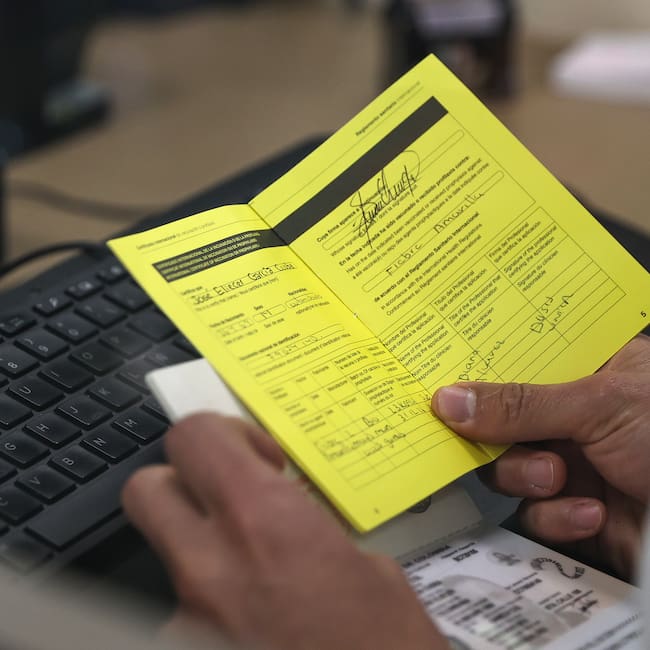 QUI01. QUITO (ECUADOR) 12/05/2025.- Un integrante del servicio de migración, revisa el certificado internacional de vacunación contra la fiebre amarilla de un turista, este lunes en el Aeropuerto Internacional Mariscal Sucre de Quito (Ecuador). El Gobierno de Ecuador comenzó exigir desde este lunes certificado de vacunación contra la fiebre amarilla a todos los viajeros que lleguen al país procedentes de Bolivia, Brasil, Colombia y Perú que hayan permanecido al menos diez días en esos países, una medida que aplica también a los propios ecuatorianos que entren a territorio ecuatoriano. EFE/José Jácome