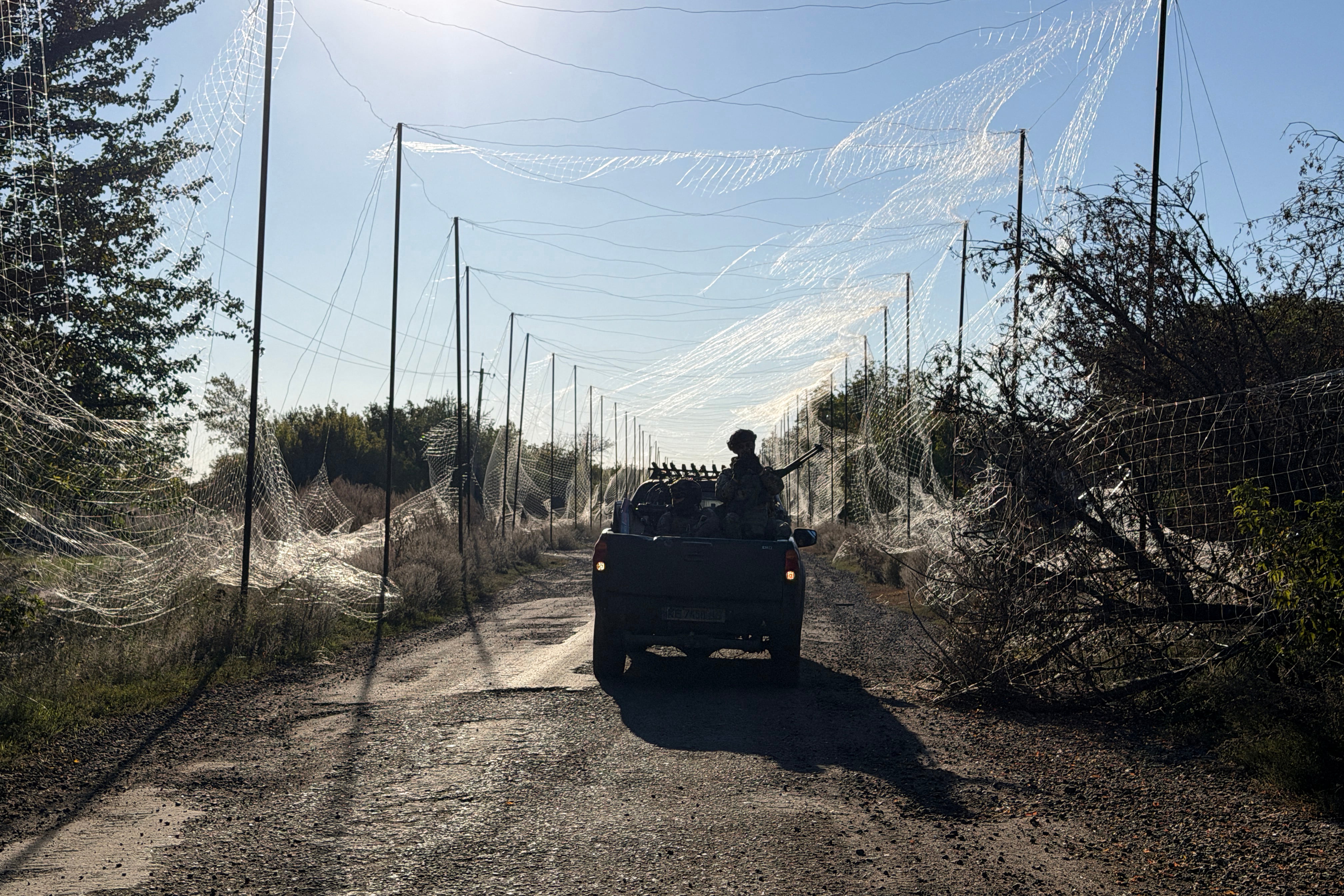 A serviceman of Ukraine's 141st Separate Mechanised Brigade rides on a pick up vehicle under the anti-drone net in Prosyana village in Dnipropetrovsk region on October 2, 2026, amid the Russian invasion of Ukraine. (Photo by Darya Nazarova (STR Zaporizhzhia) / AFP)