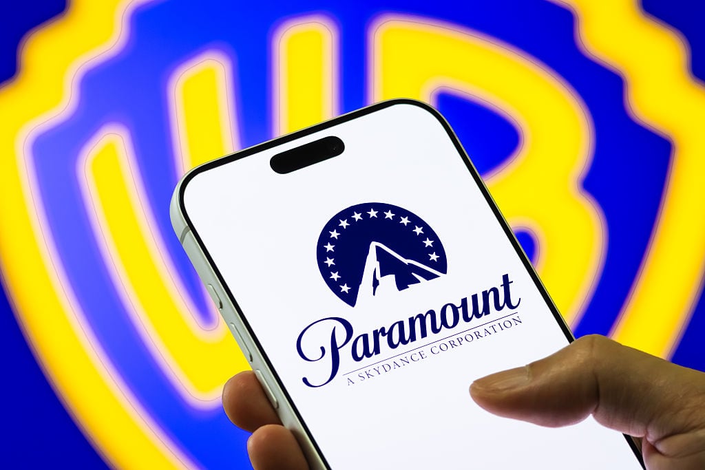 CHONGQING, CHINA  DECEMBER 6: In this photo illustration, a smartphone displays the Paramount Skydance logo in front of a blurred Warner Bros. Discovery emblem, on December 6, 2025, in Chongqing, China. Paramount Skydance had previously submitted a takeover bid for Warner Bros. Discovery before a rival bid by Netflix won the auction  part of a broader bidding war among major media companies seeking to acquire WBD's studios, streaming assets and content library. (Photo illustration by Cheng Xin/Getty Images)
