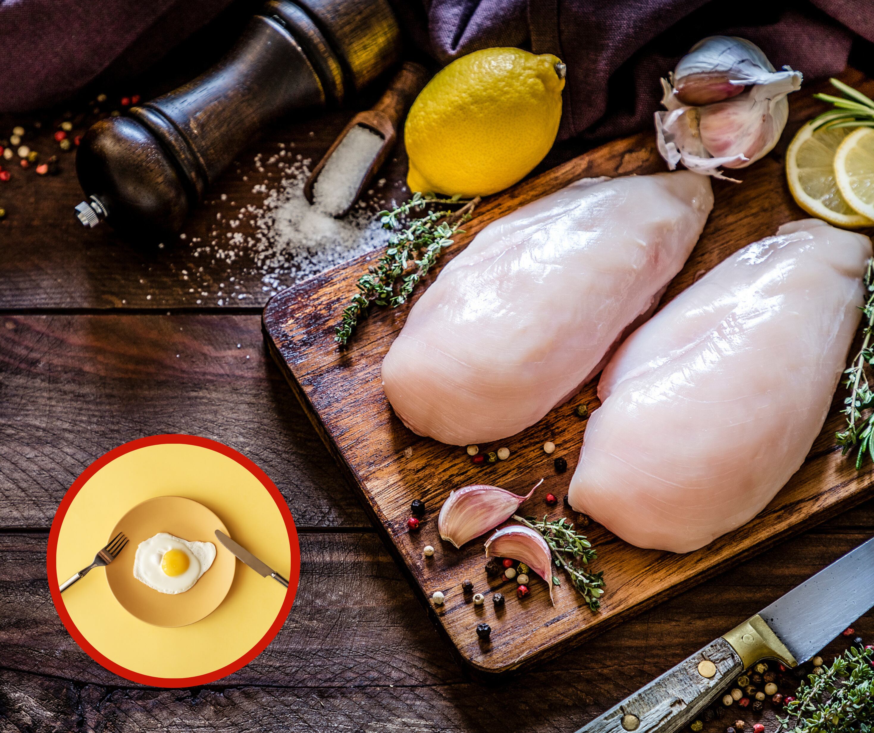 Pollo crudo sobre una tabla junto a un huevo frito sobre un plato (Foto vía Getty Images)