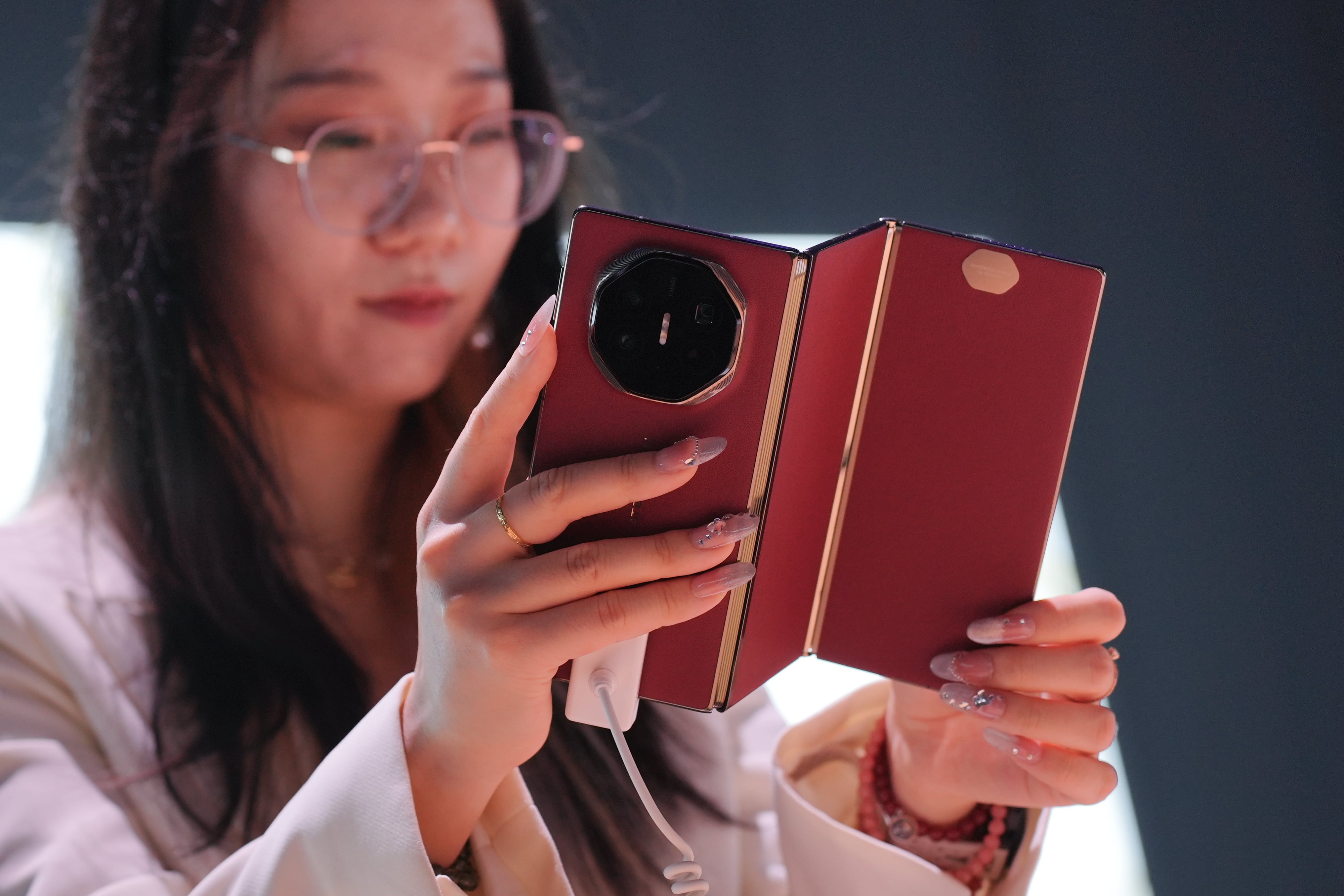 MH01. KUALA LUMPUR (MALASIA), 20/02/2025.- Una mujer sostiene un smartphone tríptico Mate XT durante un evento de presentación este martes, en Kuala Lumpur (Malasia). El nuevo as bajo la manga de Huawei es uno de los clics tecnológicos de la semana. ¿Creía que un teléfono con pantalla plegable era revolucionario? ¿O con doble pantalla plegable? Pues aquí les presentamos uno con triple pantalla plegable. EFE/EPA/ Mukhriz Hazim