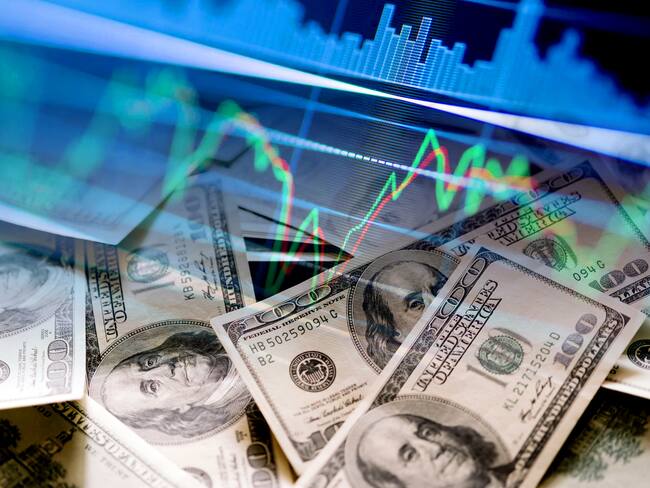Billetes de dólares en efectivo e indicadores del mercado de valores (Foto vía Getty Images)