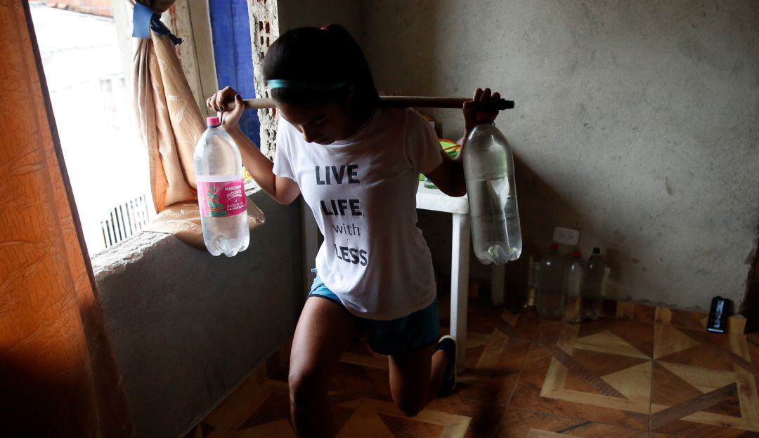 Carmen Rodallega entrenándose en su casa junto a un par de botellas llenas de agua.