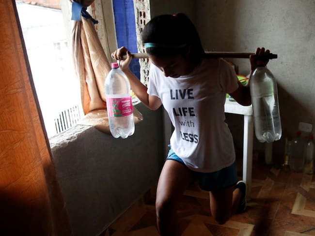 Carmen Rodallega entrenándose en su casa junto a un par de botellas llenas de agua.