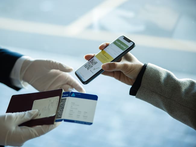 Persona mostrando los documentos de identificación y requisitos de viaje ante un agente de mygración. (Foto vía Getty Images)