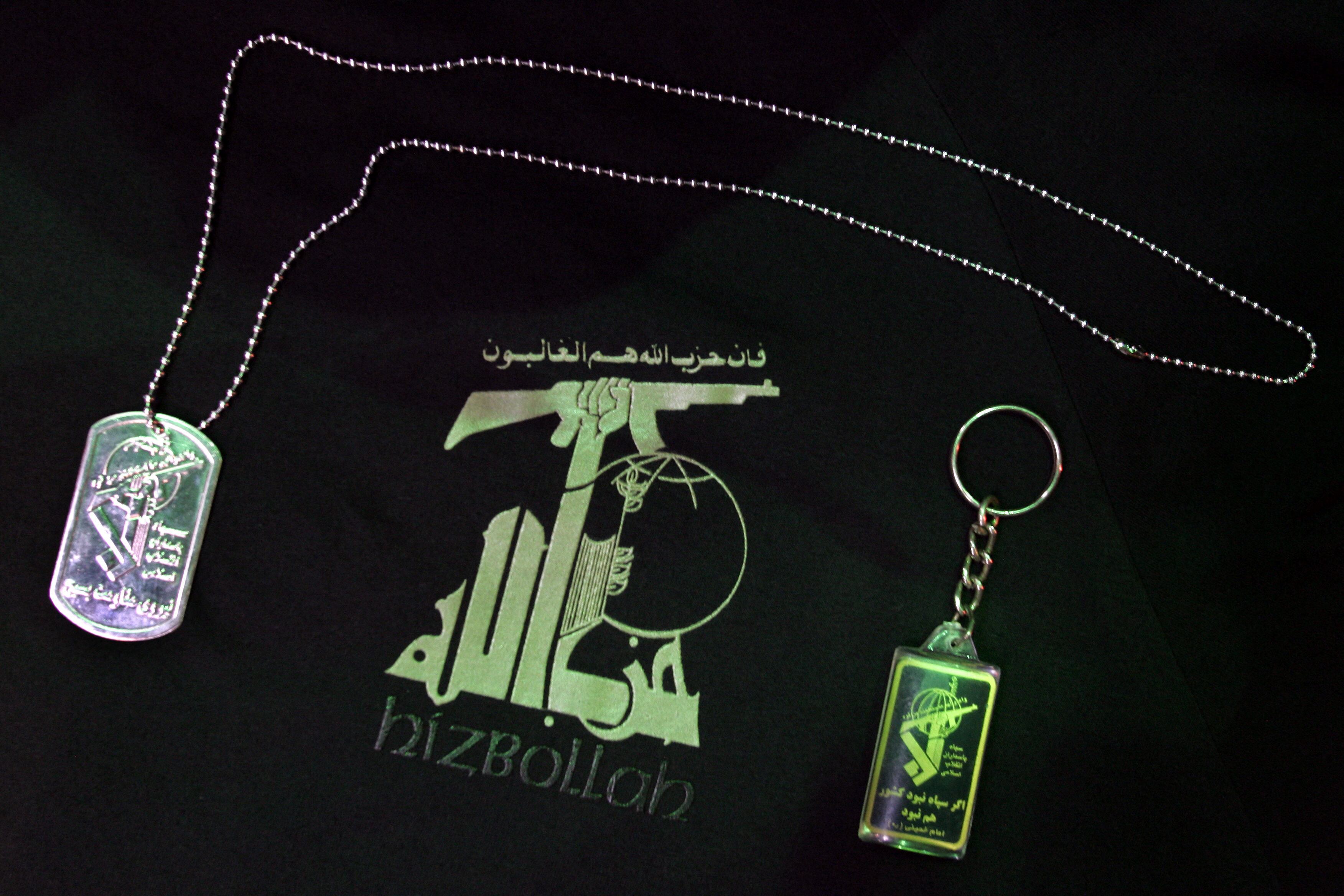 A dog tag (L) and a key ring (R) are seen on a T-shirt with the logotype of the Lebanese radical Islamic Shiite organization Hezbollah 28 July 2006 at an military supply shop, in Sao Paulo, Brazil. According to its owner the demand for Hezbollah T-shirts has increased after the beginning of Israeli military offensive on Lebanon  AFP PHOTO/Mauricio LIMA (Photo by MAURICIO LIMA / AFP) (Photo by MAURICIO LIMA/AFP via Getty Images)