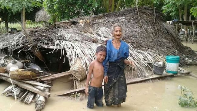 Una mujer y su nieto junto a su casa destruida por las inundaciones que han afectado a Indonesia.