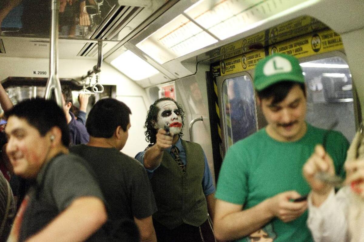31 de octubre 2014. Un hombre vestido del súper villano de DC Cómics, el Joker, apunta con un arma de juguete mientras se posa en un vagón de metro en Santiago, Chile.