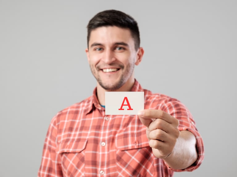 Hombre mostrando la letra A en un papel (Fotos vía Getty Images)