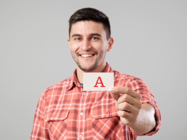 Hombre mostrando la letra A en un papel (Fotos vía Getty Images)
