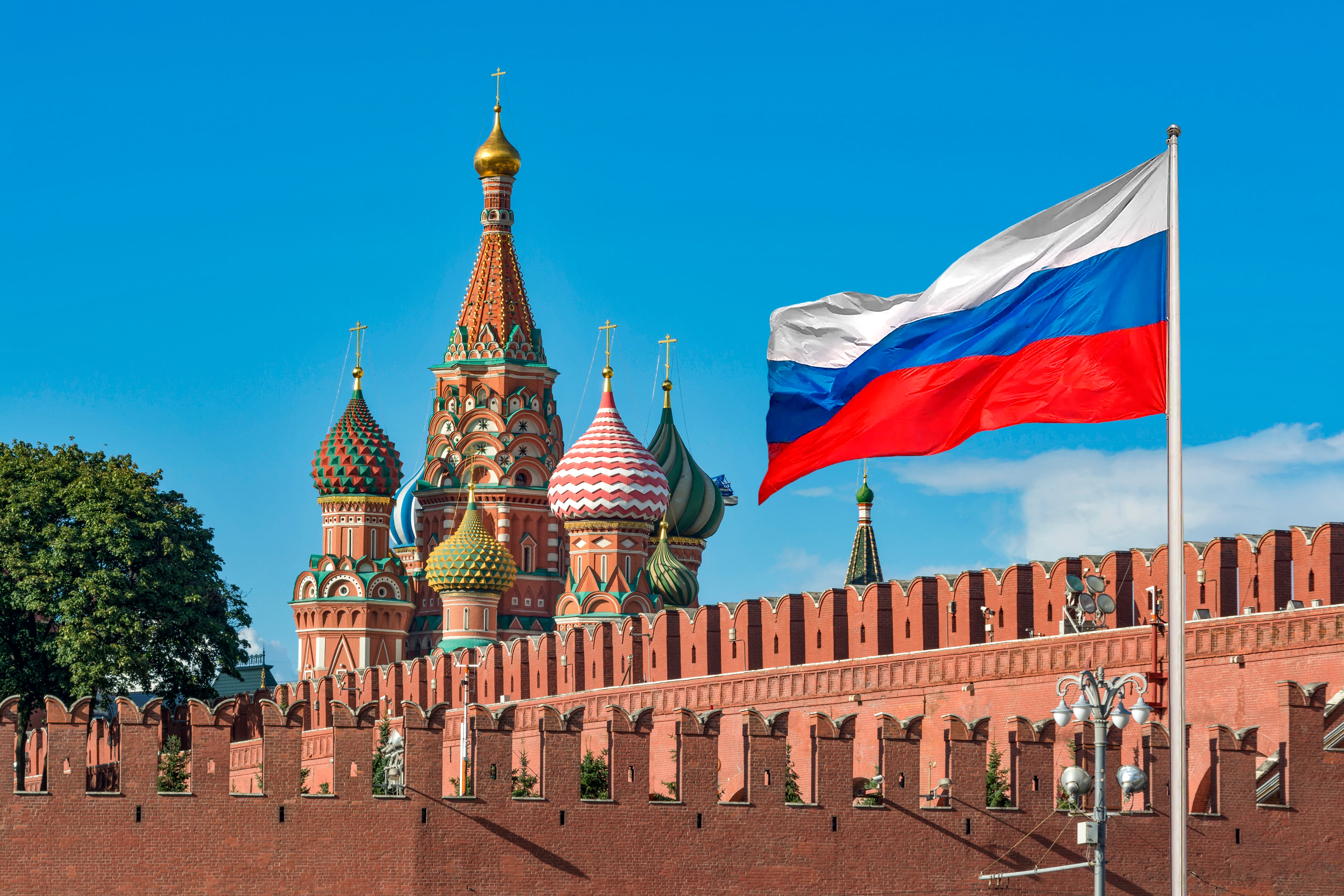 View of The national flag of the Russian Federation with view of The Moscow Kremlin's Walls and  St Basil's Cathedral at sunny day in Moscow, Russia