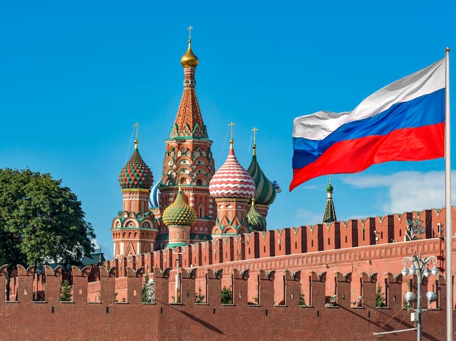 View of The national flag of the Russian Federation with view of The Moscow Kremlin's Walls and St Basil's Cathedral at sunny day in Moscow, Russia