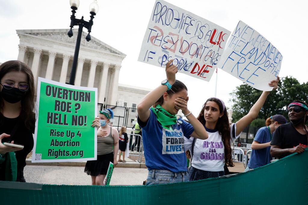 WASHINGTON, DC - JUNE 24:  Abortion-rights activists Carrie McDonald  (C) and Soraya Bata react to the Dobbs v Jackson Women's Health Organization ruling in front of the U.S. Supreme Court on June 24, 2022 in Washington, DC. The Court's decision in Dobbs v Jackson Women's Health overturns the landmark 50-year-old Roe v Wade case and erases a federal right to an abortion. (Photo by Anna Moneymaker/Getty Images)