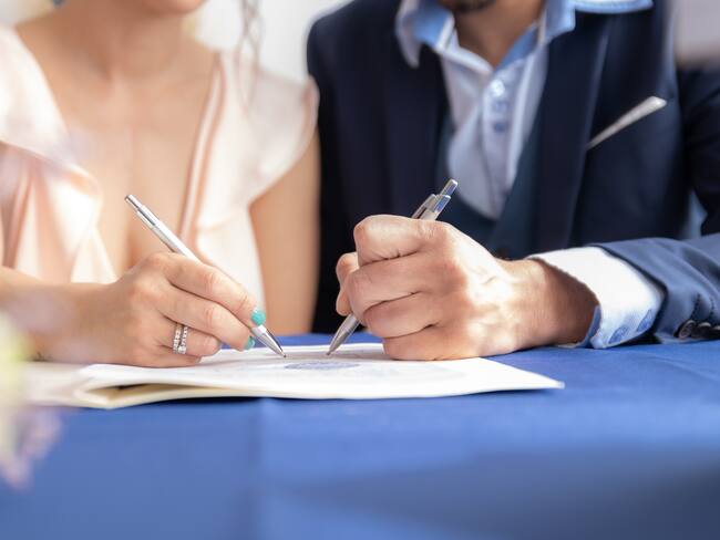 Imagen referencial de un hombre y una mujer firmando un certificado de matrimonio. GettyImages.