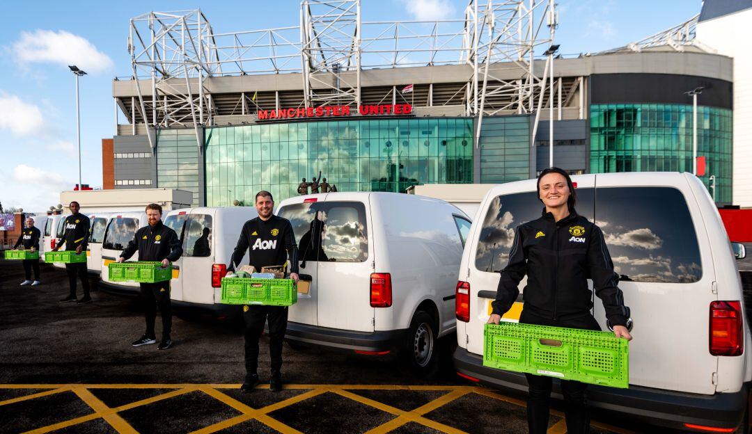 Personal del Manchester United con las cajas llenas de productos para ser repartidos.