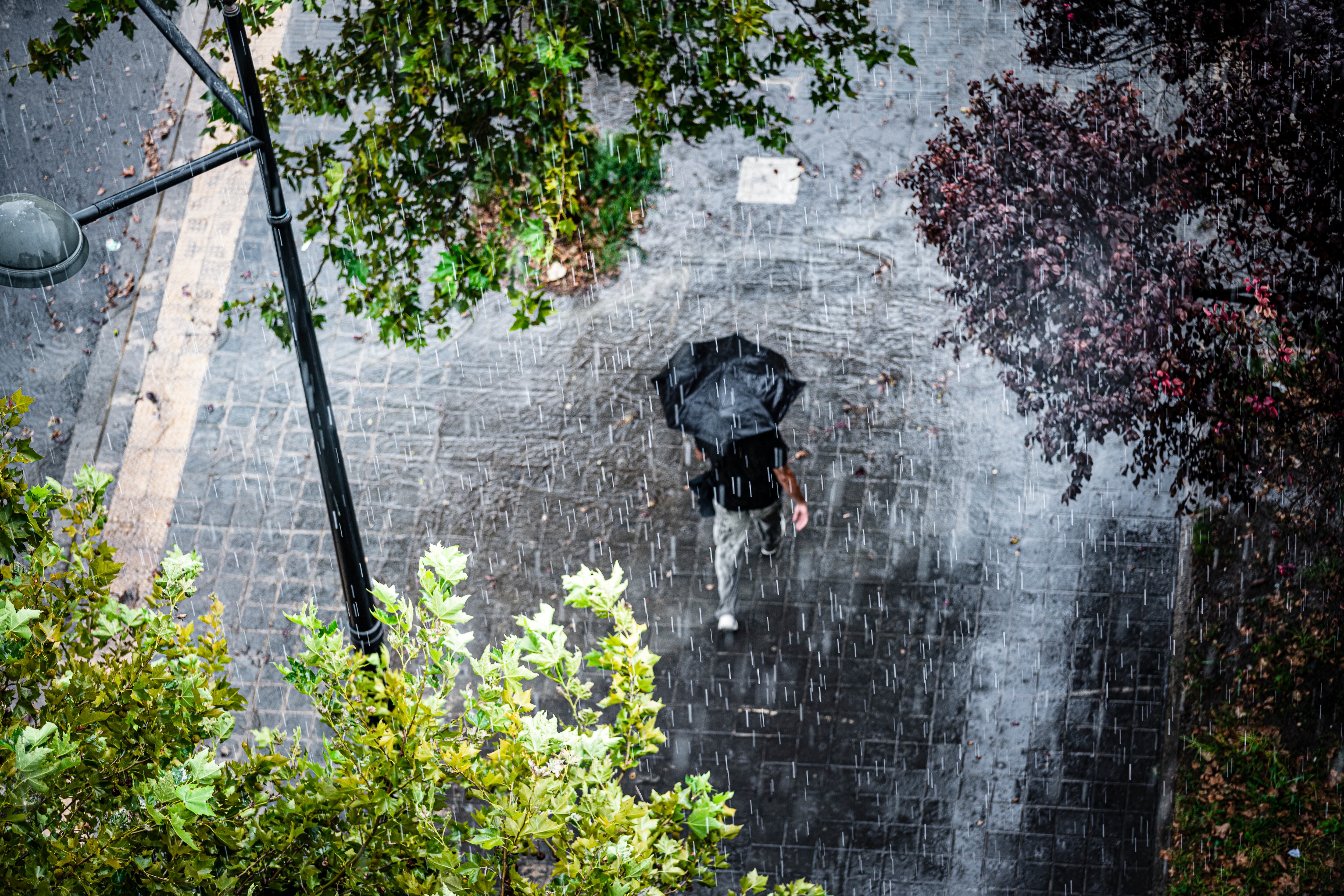Persona con sombrilla en medio de una fuerte lluvia (Getty Images)