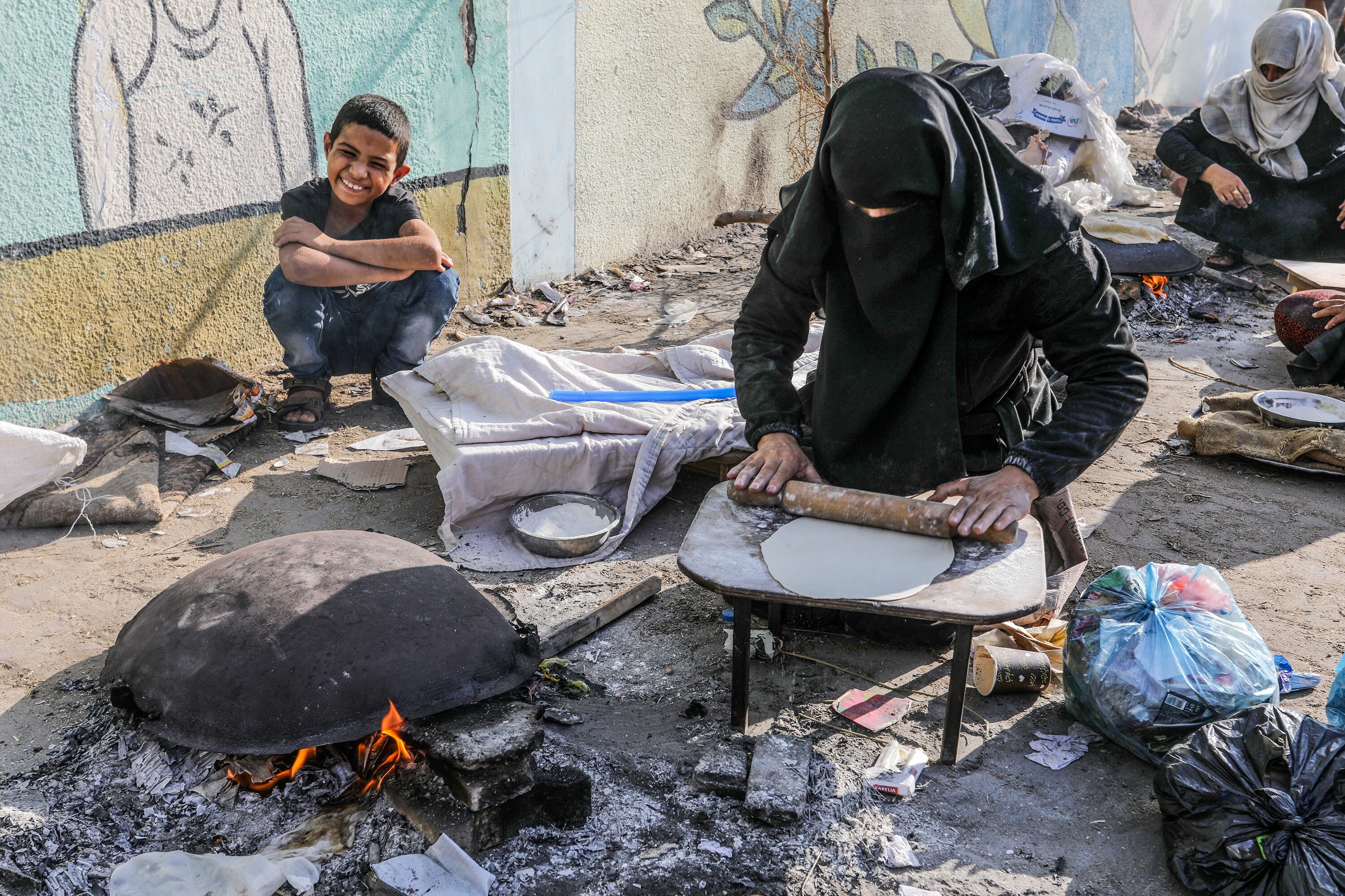 RAFAH, GAZA - OCTOBER 27: Palestinians meet their daily food needs by baking bread on a sheet pan under difficult conditions in a school of the United Nations Relief and Works Agency for Palestine Refugees in the Near East (UNRWA) where they take shelter during the 21st day of Israeli airstrikes in Rafah, Gaza on October 27, 2023. (Photo by Abed Rahim Khatib/Anadolu via Getty Images)