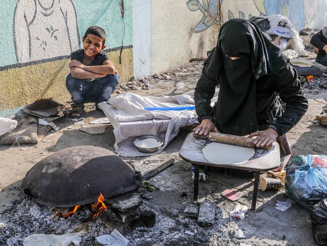 RAFAH, GAZA - OCTOBER 27: Palestinians meet their daily food needs by baking bread on a sheet pan under difficult conditions in a school of the United Nations Relief and Works Agency for Palestine Refugees in the Near East (UNRWA) where they take shelter during the 21st day of Israeli airstrikes in Rafah, Gaza on October 27, 2023. (Photo by Abed Rahim Khatib/Anadolu via Getty Images)