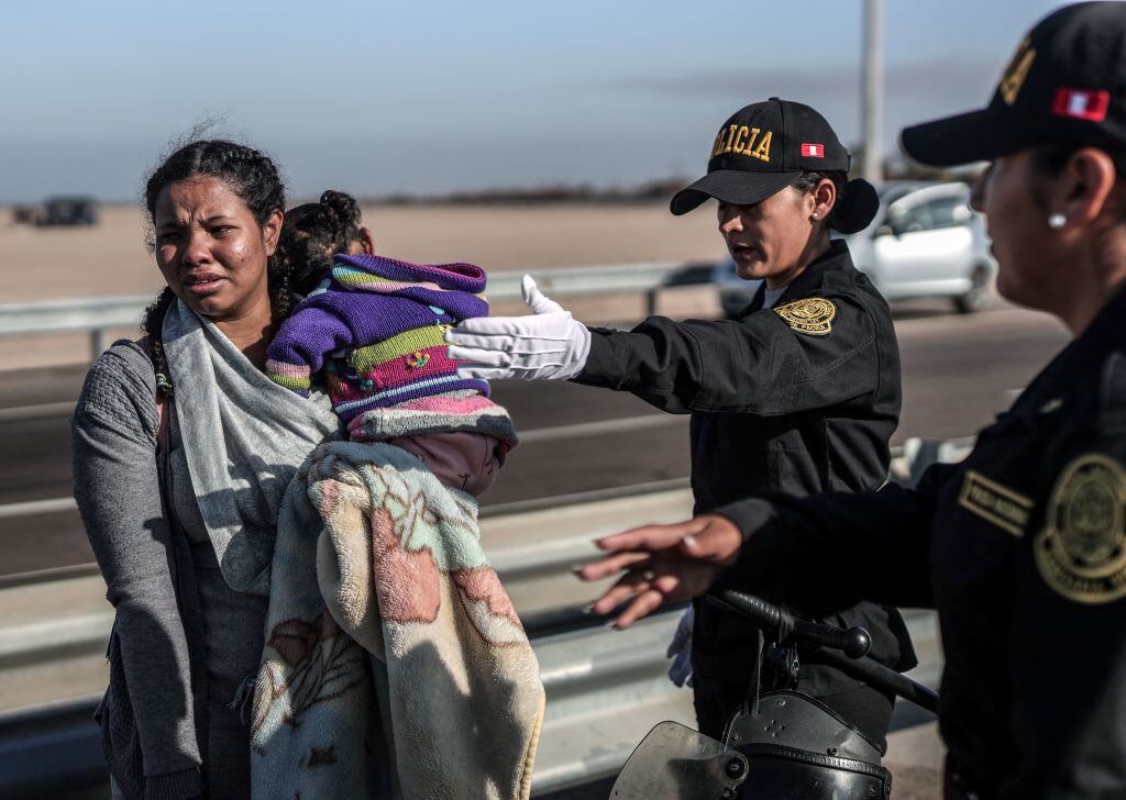 A migrant woman is escorted by Peruvian police officers to a migration office in Tacna, in the Peru-Chile border on April 28, 2023. - Peru mobilized 200 police officers to the southern border after the Chilean Congress approved two laws allowing the detention of irregular migrants without papers and extending the detention period to manage their expulsion. Peru, Chile, Ecuador, and Venezuela are considering opening a humanitarian corridor so that hundreds of migrants leaving Chilean territory can cross to their countries of origin, Peruvian Interior Minister Vicente Romero reported. (Photo by ALDAIR MEJIA / AFP) (Photo by ALDAIR MEJIA/AFP via Getty Images)