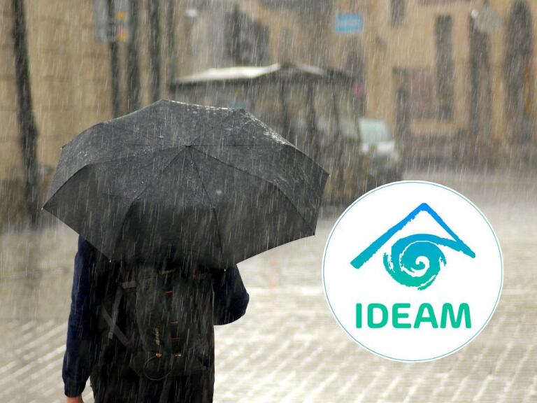 Hombre con sombrilla mientras llueve fuerte en el centro de la ciudad (Getty Images) / Logo del IDEAM