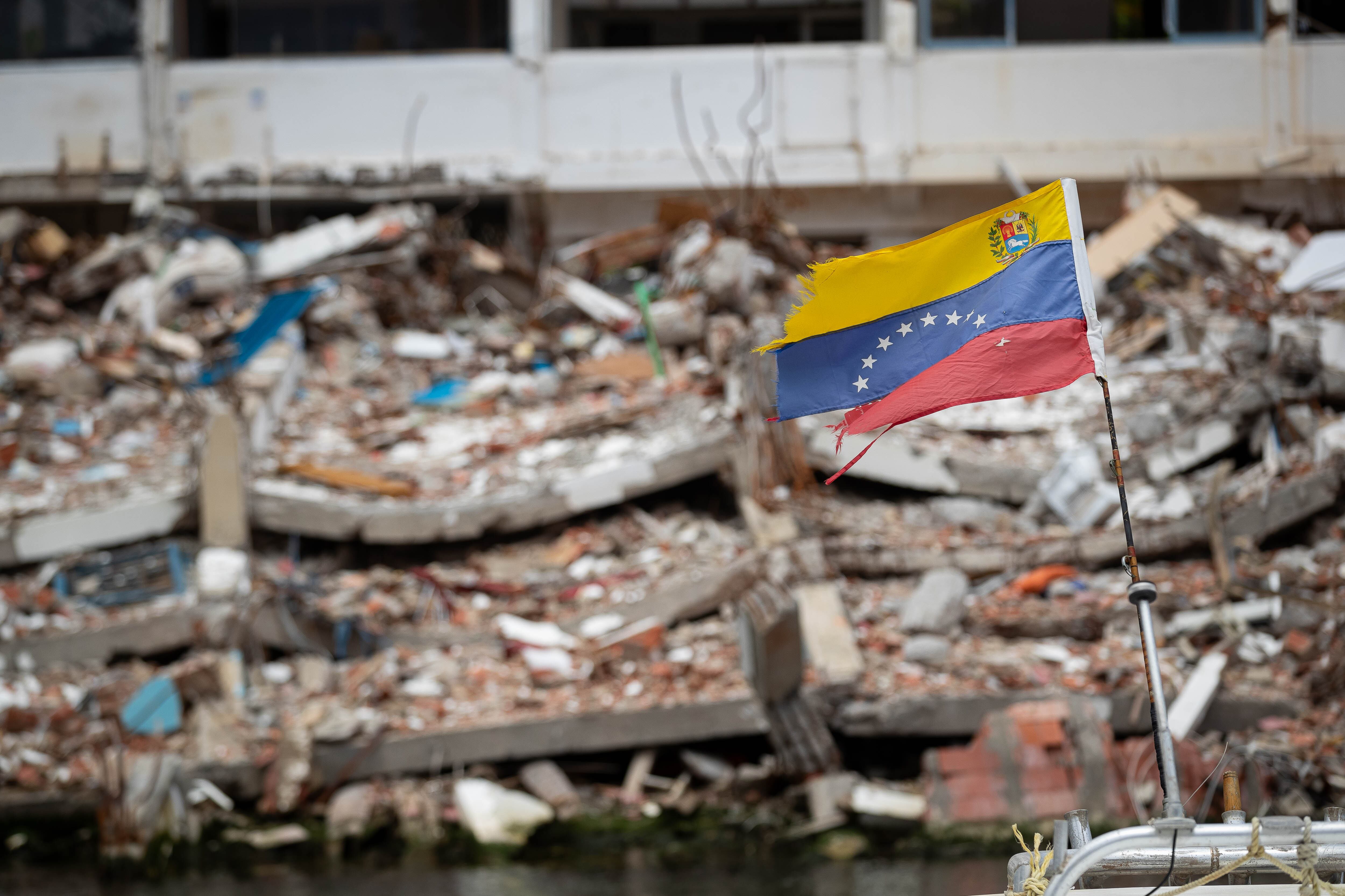 Fotografía de una bandera de Venezuela frente a un edificio colapsado por los terremotos del 24 junio,  en La Guaira (Venezuela). EFE/ Ronald Peña R