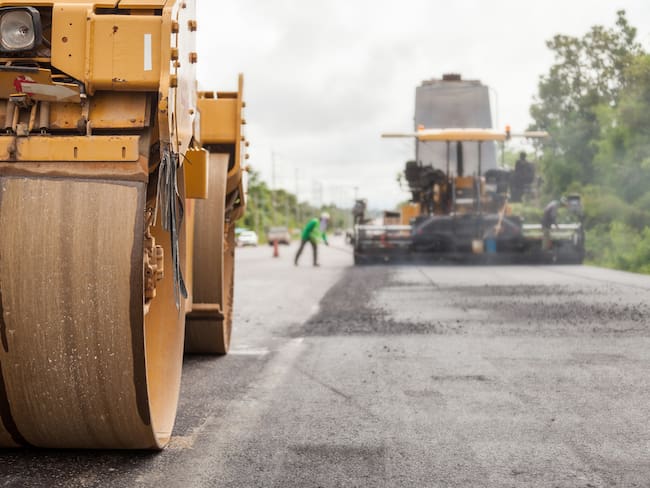 Road construction works with roller compactor machine and asphalt finisher.