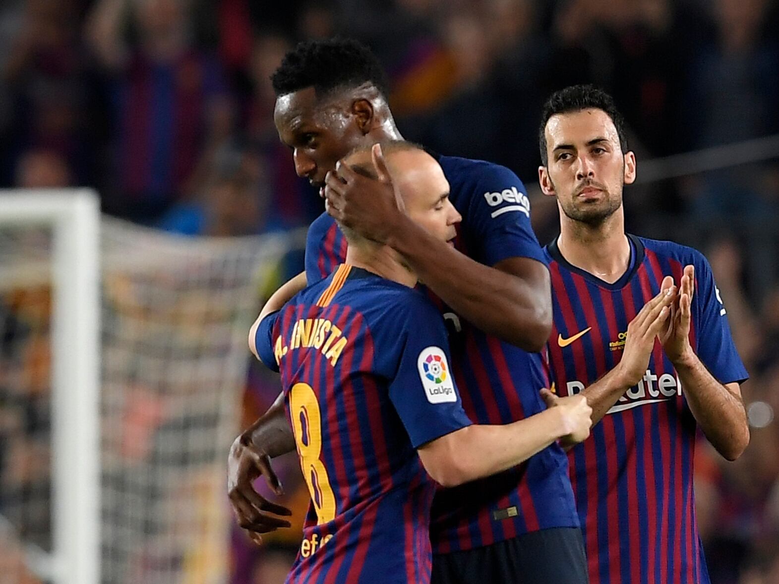 Barcelona's Spanish midfielder Andres Iniesta (L) hugs Barcelona's Colombian defender Yerry Mina (C) next to Barcelona's Spanish midfielder Sergio Busquets during the Spanish league football match between FC Barcelona and Real Sociedad at the Camp Nou stadium in Barcelona on May 20, 2018. - Iniesta, who joined Barcelona's academy 22 years ago, played his final game for the club. (Photo by LLUIS GENE / AFP) (Photo credit should read LLUIS GENE/AFP via Getty Images)