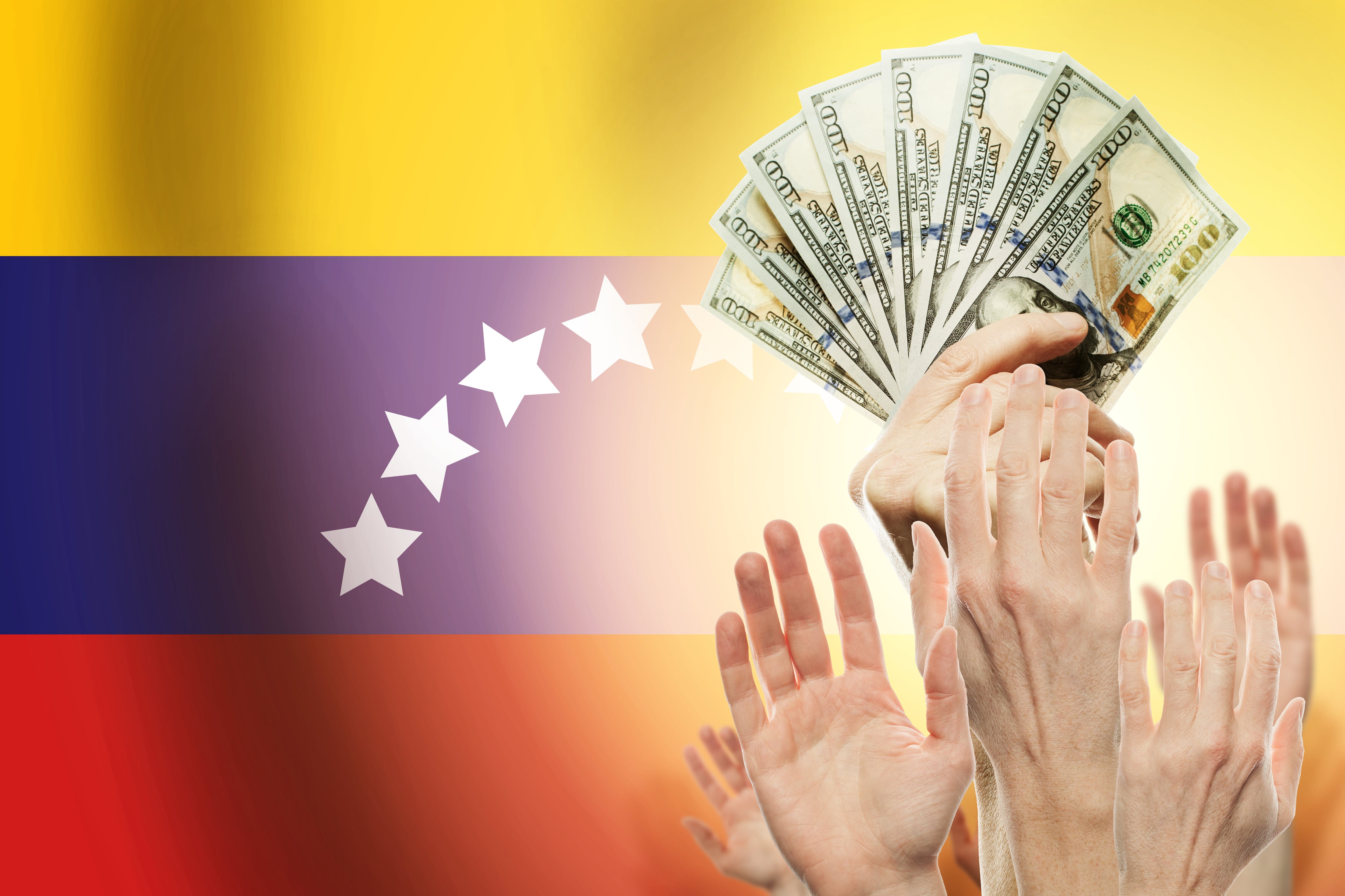 People raising hands with dollars and flag Venezuela on background. (Credito: 	JNemchinova // Getty imagenes)