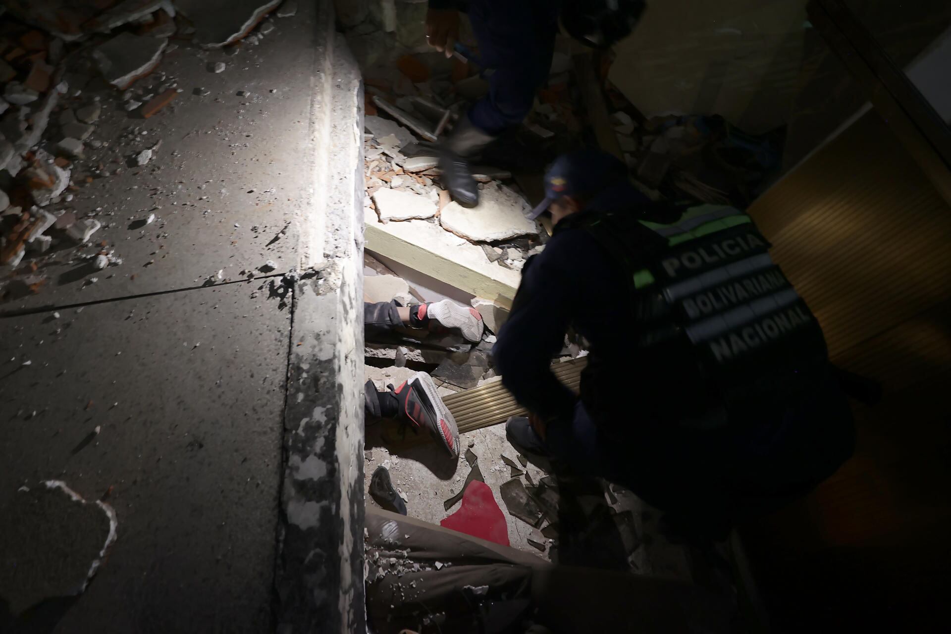 Uniformado de la Policía intenta rescatar a una persona atrapada por terremoto en Venezuela. Foto: EFE.