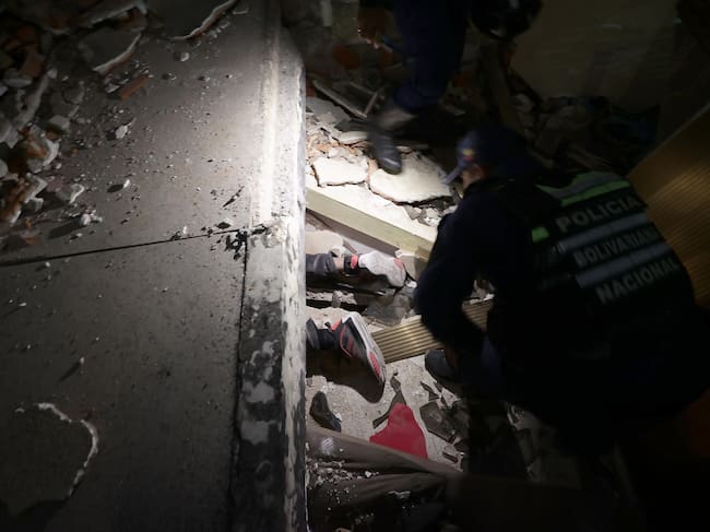 Uniformado de la Policía intenta rescatar a una persona atrapada por terremoto en Venezuela. Foto: EFE.