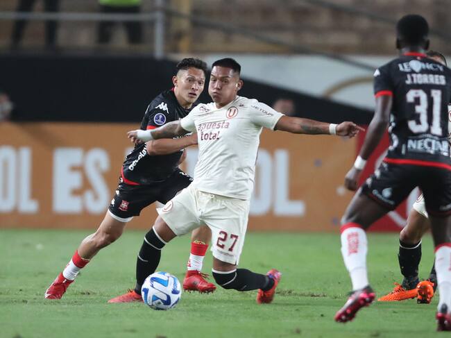 Nelson Cabanillas de Universitario disputa hoy el balón con Wilfrido de la Rosa (i) de Santa Fe, durante un partido por el Grupo G de la Copa Sudamericana en el Estadio Monumental en Lima (Perú). EFE/ Paolo Aguilar