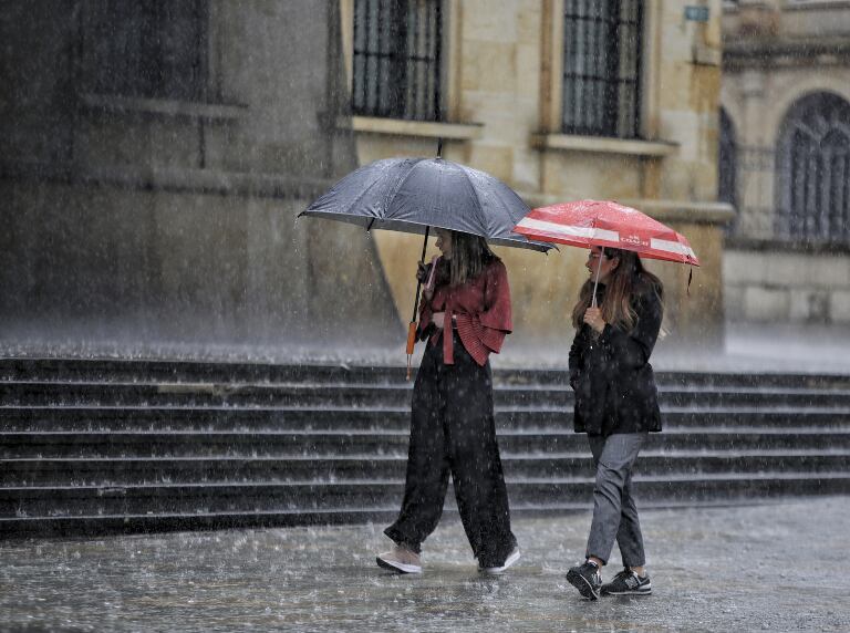 Mujeres caminando por el centro de Bogotá con sombrilla mientras llueve (Getty Images)