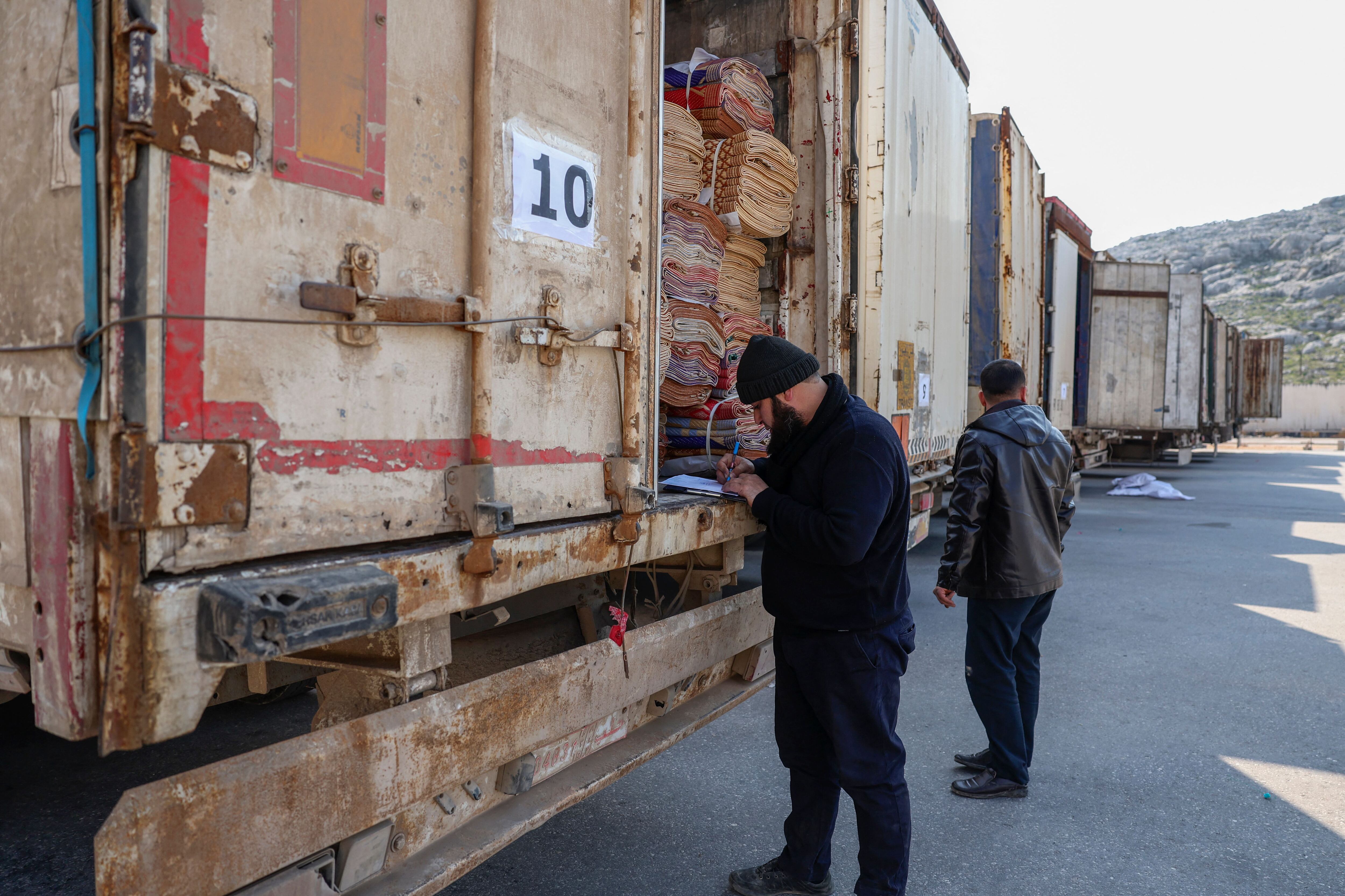 A clerk inspects the cargo of a truck among a convoy carrying tent and shelter kits provided by the United Nations in the aftermath of a deadly earthquake, at Syria's Bab al-Hawa border crossing with Turkey in the rebel-held northwestern province of Idlib, on February 12, 2023. (Photo by OMAR HAJ KADOUR / AFP) (Photo by OMAR HAJ KADOUR/AFP via Getty Images)