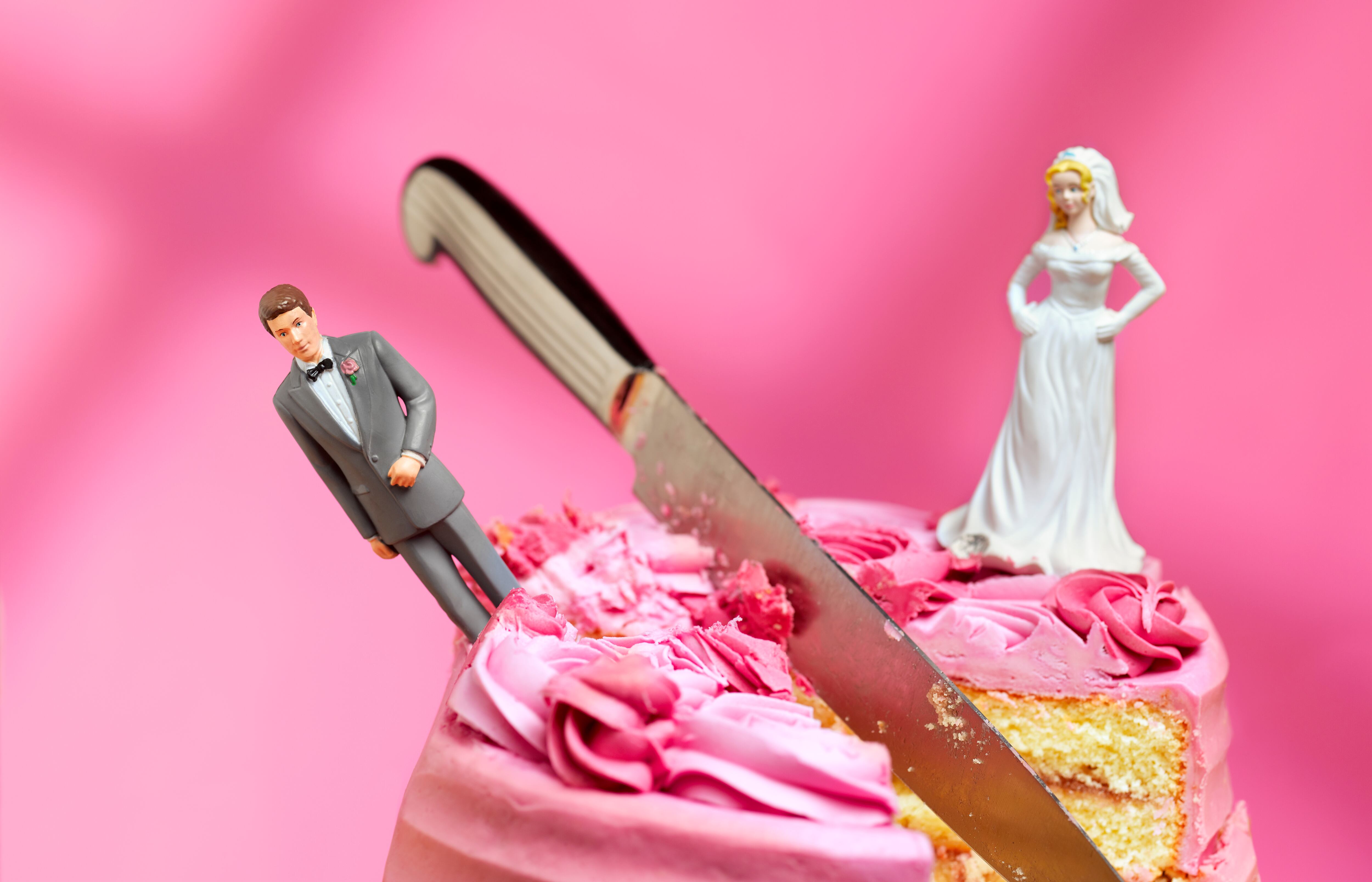 knife cutting between bride and groom figurines, relationship breakup