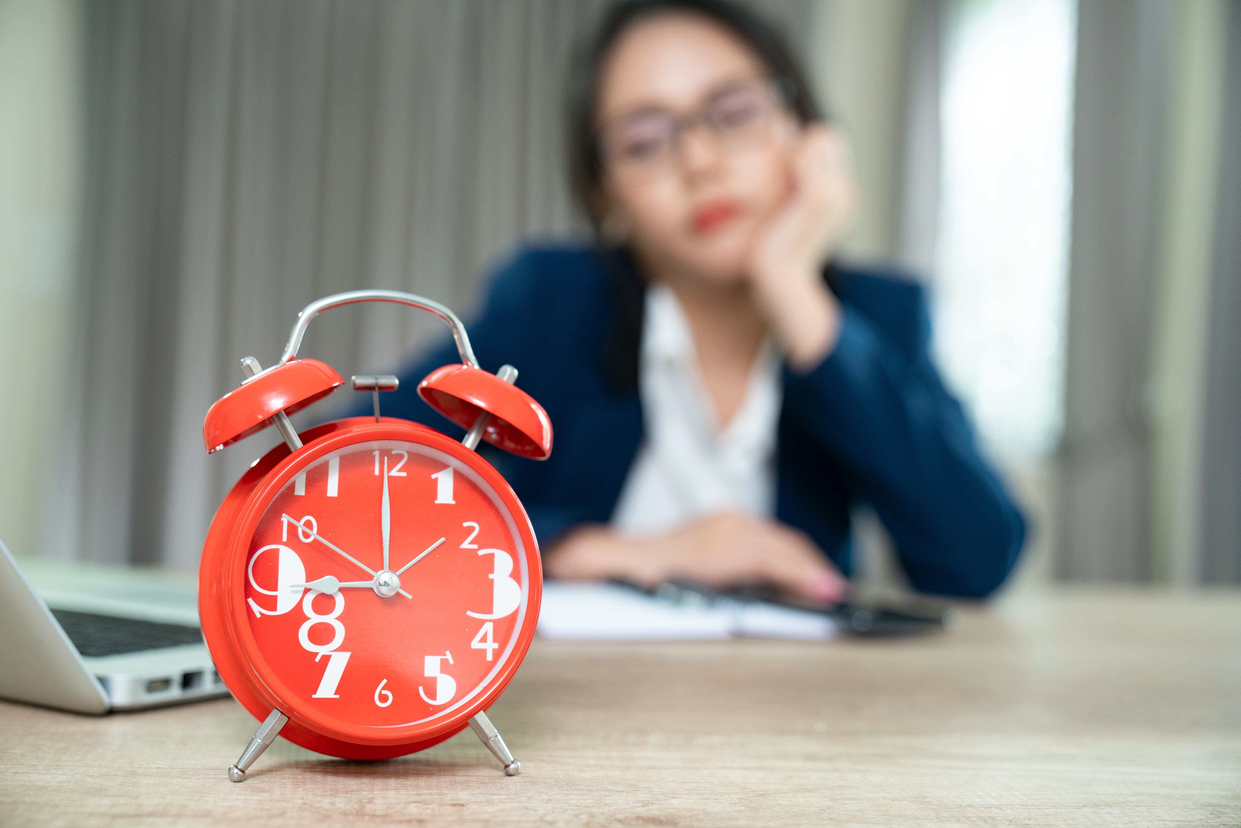 Imagen de referencia. Trabajadora observando reloj de mesa esperando hora de salida: Getty Images. 