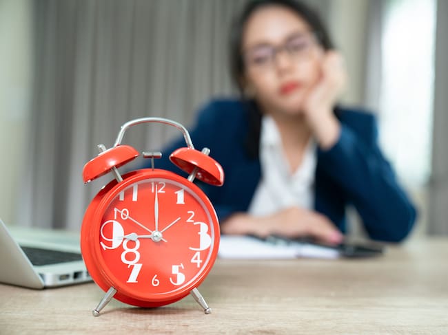 Imagen de referencia. Trabajadora observando reloj de mesa esperando hora de salida: Getty Images.