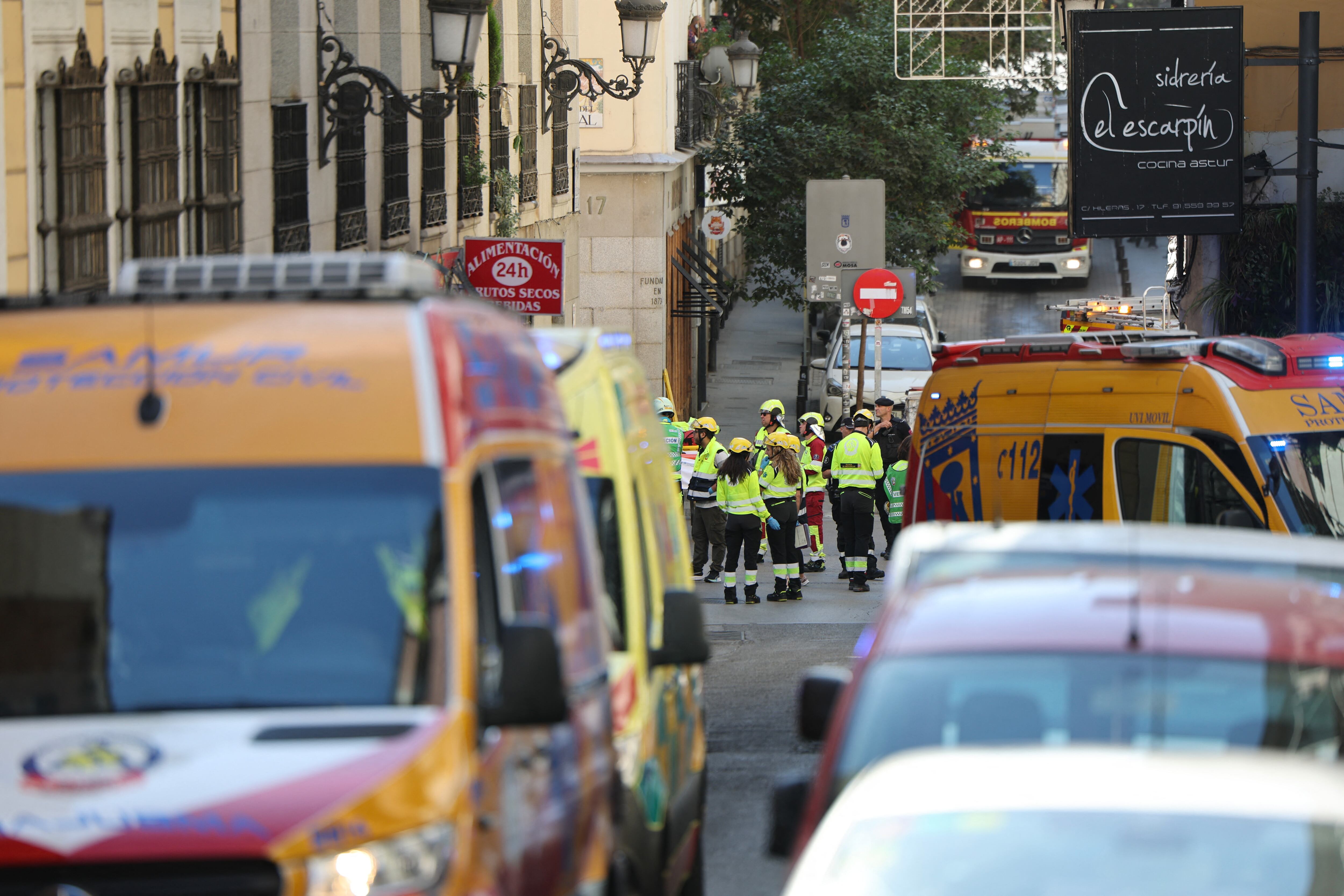 Police and emergency service workers are seen near the site of a collapsed building undergoing refurbishment in Madrid on October 7, 2025. Spanish emergency services scrambled to a building collapse in Madrid's touristic city centre on Tuesday with local media reporting several people missing. Emergency services said on X that firefighters were working at the scene of a building undergoing refurbishment near the Spanish capital's opera. (Photo by Thomas COEX / AFP)