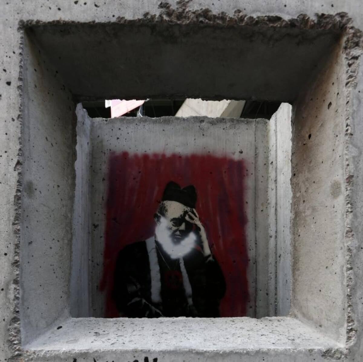 Un viandante hace una foto del graffiti "Confesionario de hormigón (Concrete Confessional)" del artista callejero británico.