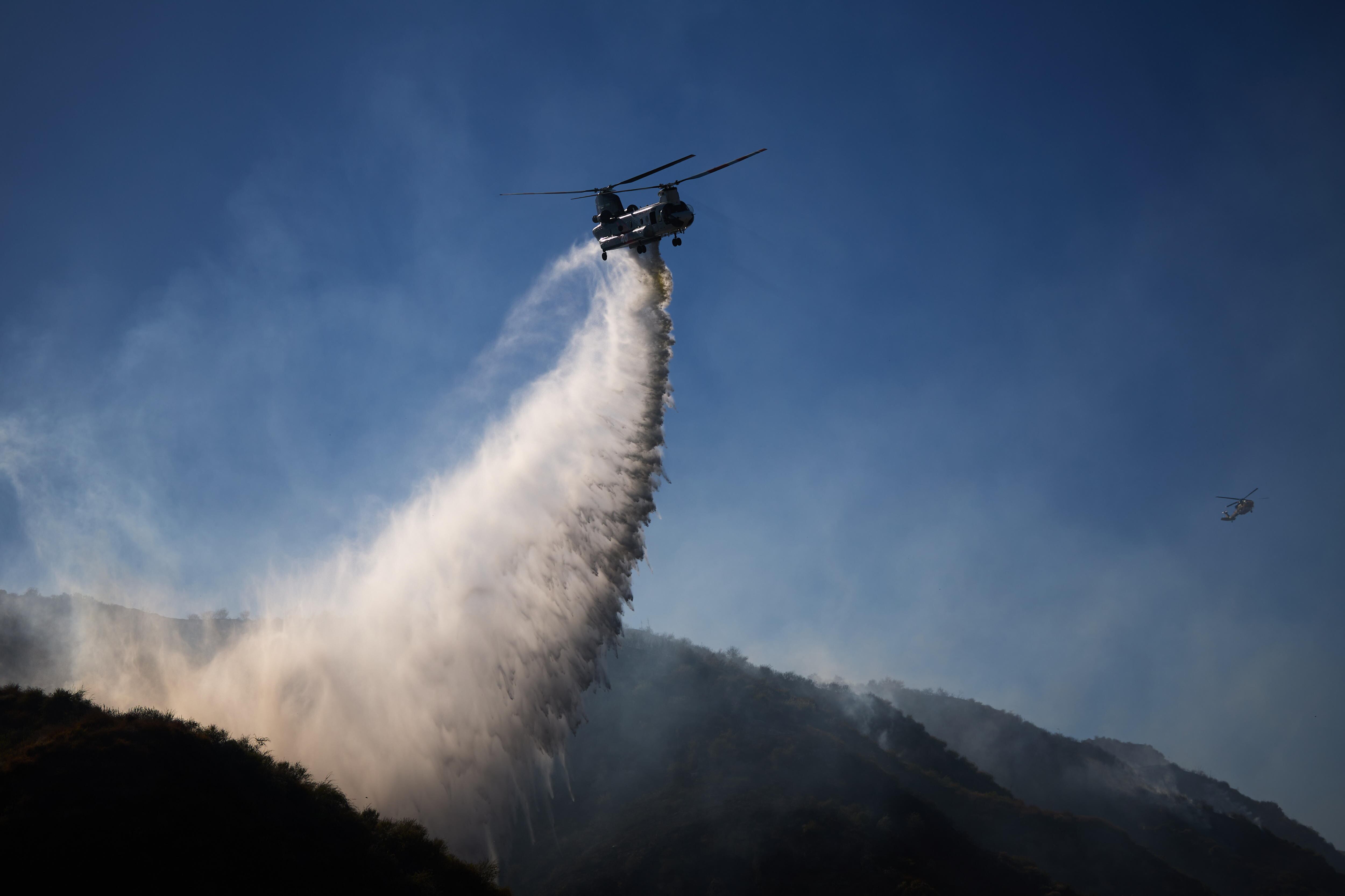 Simi Valley (United States), 04/07/2024.- A helicopter drops water on the Sharp Fire as fire crews battle the fire in Simi Valley, California, USA, 03 July 2024.