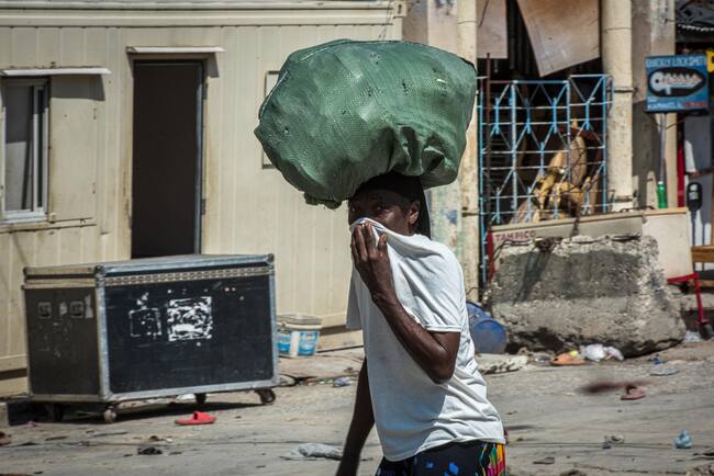 AME5375. PUERTO PRÍNCIPE (HAITÍ), 04/03/2024.- Una mujer camina frente a la prisión nacional este lunes, en Puerto Príncipe (Haití). La actividad está paralizada este lunes en el centro de Puerto Príncipe tras varios días de violencia marcados por el asalto de miembros de bandas armadas en la noche del sábado a la cárcel civil de la capital, de donde se fugó más del 97 % del total de los reclusos y al menos 15 de ellos murieron. EFE/ Johnson Sabin