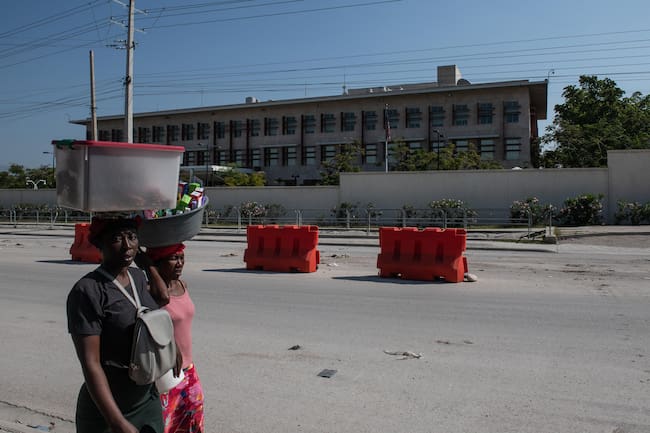 AME8040. PUERTO PRÍNCIPE (HAITÍ), 12/03/2024.- Dos mujeres caminan frente a la embajada de Estados Unidos, este martes en Puerto Príncipe (Haití). El Gobierno de Estados Unidos afirmó este martes que espera que el nombramiento de un nuevo primer ministro haitiano suceda &quot;sin más demora&quot; después de que el actual, Ariel Henry, anunciara su dimisión. La salida de Henry solo será efectiva una vez se forme un &quot;consejo presidencial de transición&quot;, algo que según Miller debe ocurrir en las próximas 24 o 48 horas, y este se ponga de acuerdo en el nombramiento del nuevo primer ministro. EFE/ Johnson Sabin