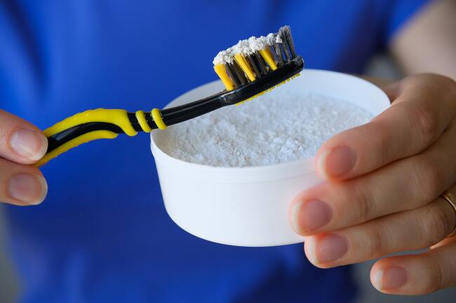 Persona colocando un poco de bicarbonato de sodio en el cepillo de dientes (Getty Images)