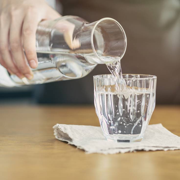 Persona sirviendo agua en un vaso de cristal (Foto vía Getty Images)